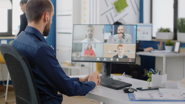 Zakenman praten met team van collega's op video-oproep voor project briefing op kantoor. Ingenieur die online conferentie op computer gebruikt voor vergadering over bedrijfsstrategie en ontwikkeling