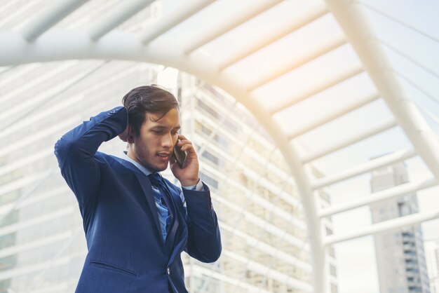 Zakenman praten over de telefoon tegen het gebouw buitenshuis.