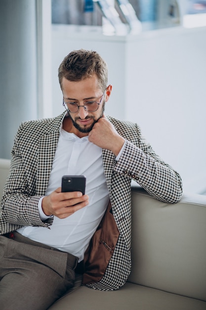 Zakenman zittend op een bank en met behulp van telefoon