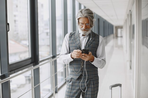 Zakenreis. Corporate en mensen concept. Man in een grijs pak. Oudste met telefoon en hoofdtelefoon.
