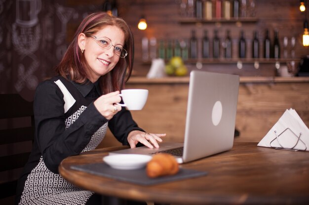 Zakenvrouw die lacht terwijl ze een kopje koffie drinkt. Koffie drinken in een vintage coffeeshop