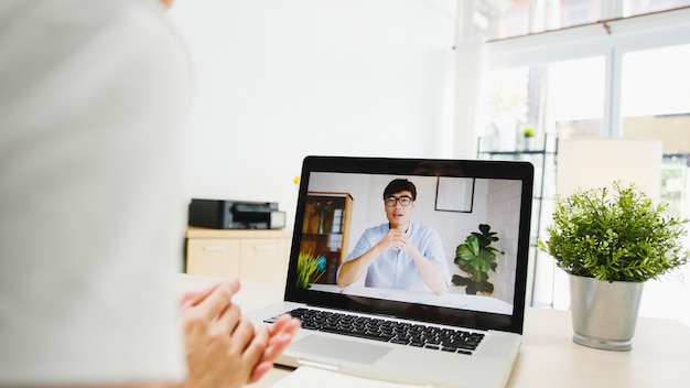 zakenvrouw die laptop gebruikt, praat met collega's over het plan in een videogesprekvergadering terwijl ze vanuit huis in de woonkamer werkt.