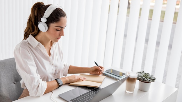 Zakenvrouw die met laptop en hoofdtelefoons werkt