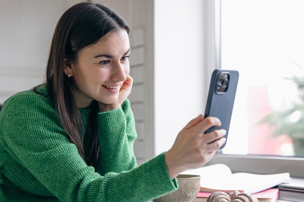 Zakenvrouw in de ochtend in de keuken met een smartphone