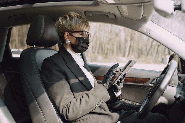 Zakenvrouw in een zwart masker zitten in een auto