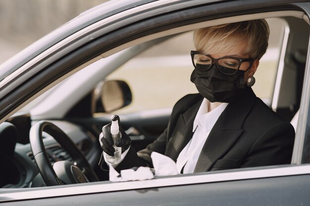 Zakenvrouw in een zwart masker zitten in een auto