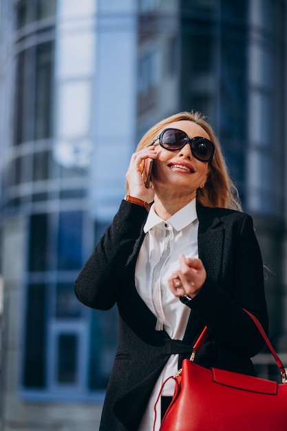 Zakenvrouw in stijlvolle outfit praten aan de telefoon bij het business center