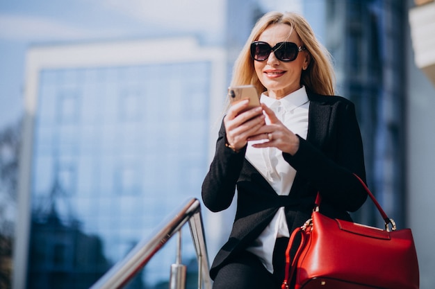 Zakenvrouw in stijlvolle outfit praten aan de telefoon bij het business center