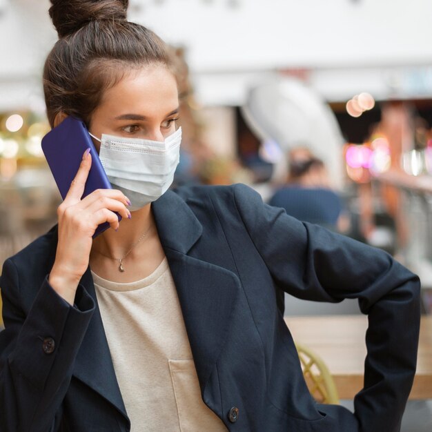 Zakenvrouw met medisch masker praten op haar telefoon