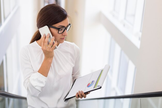 Zakenvrouw praten aan de telefoon terwijl op een roltrap