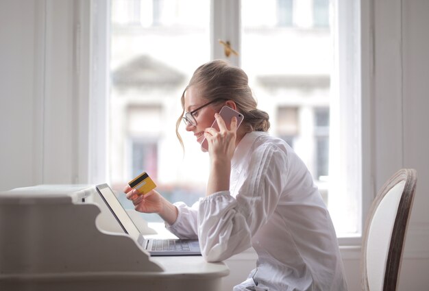 Zakenvrouw praten over de telefoon met een creditcard en glimlachen