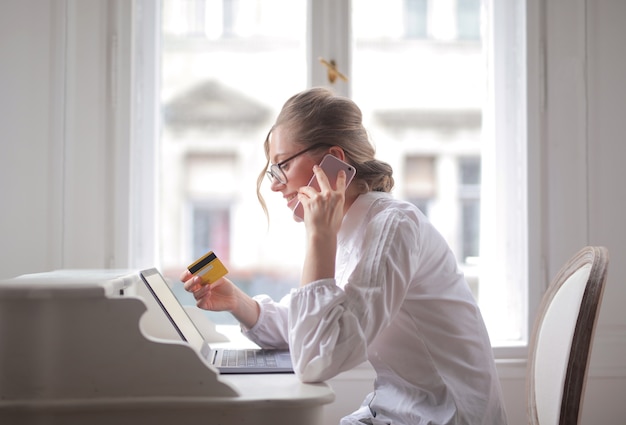 Zakenvrouw praten over de telefoon met een creditcard en glimlachen