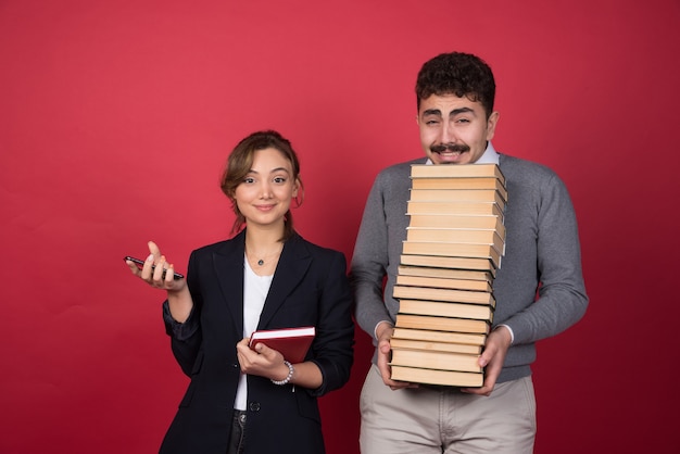 Zakenvrouw staande in de buurt van brunette man met stapel boeken