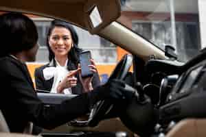 Gratis foto zakenvrouw toont haar smartphone-app aan de taxichauffeur