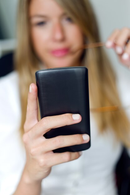 Zakenvrouw werken met mobiele telefoon in haar kantoor.