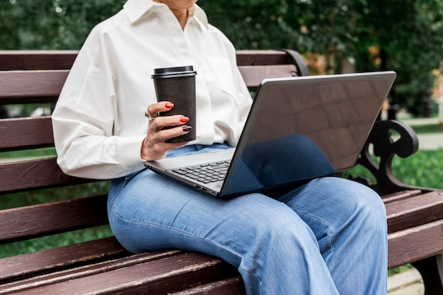 Gratis foto zakenvrouw zittend op een bankje met laptop