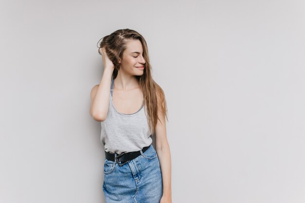 Zalig wit meisje in casual outfit poseren. Binnen schot van gelukkige jonge vrouw met lang kapsel positieve emoties uitdrukken.