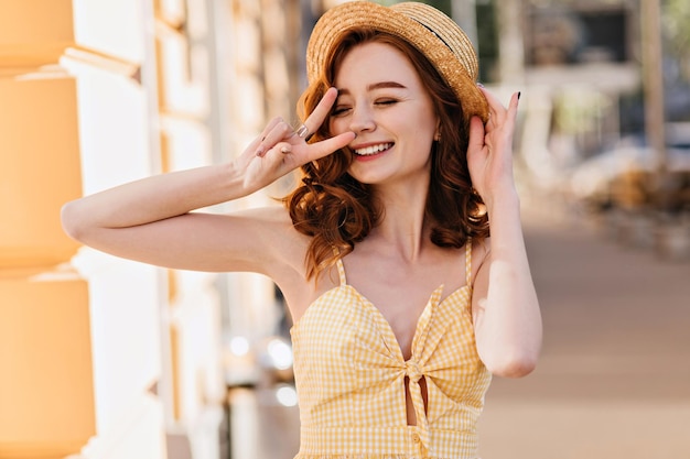 Zalig wit meisje met rood haar dat plezier heeft in de zomer Openluchtportret van stijlvol vrouwelijk model met golvend kapsel dat in het weekend chillt