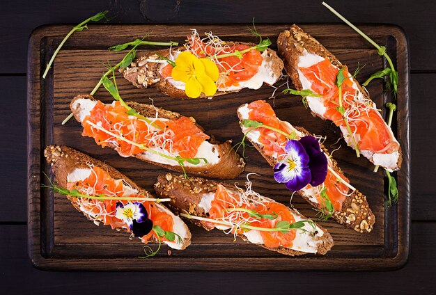 Zalmsandwiches met roomkaas en microgreen op houten lijst. Canapé met zalm.