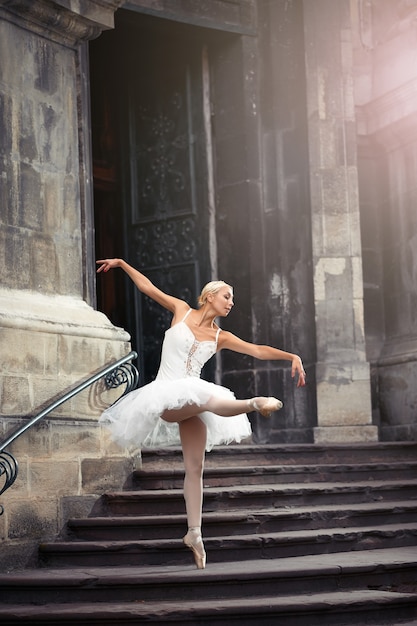 Ze ging op zoek naar inspiratie. Volledig portret van een ballerina die sierlijk danst in de buurt van een oud huis old