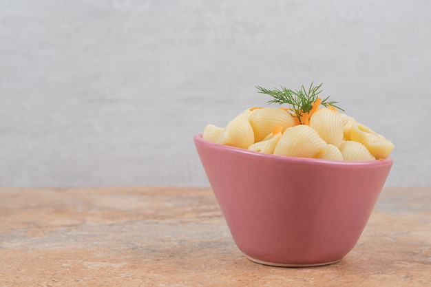 Zeeschelpvormige pasta met wortelschijfjes en dille in kom