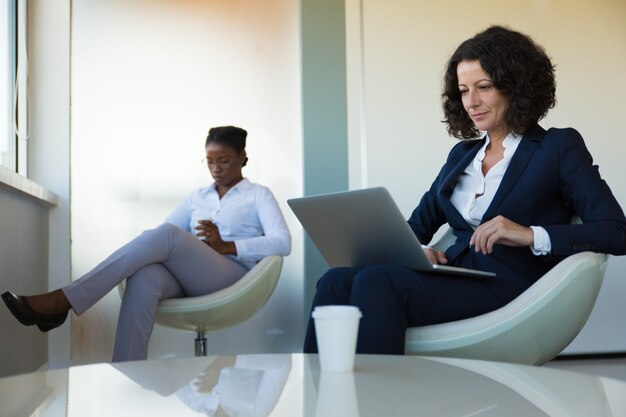 Zekere bedrijfsleider die aan computer in bureaulounge werkt