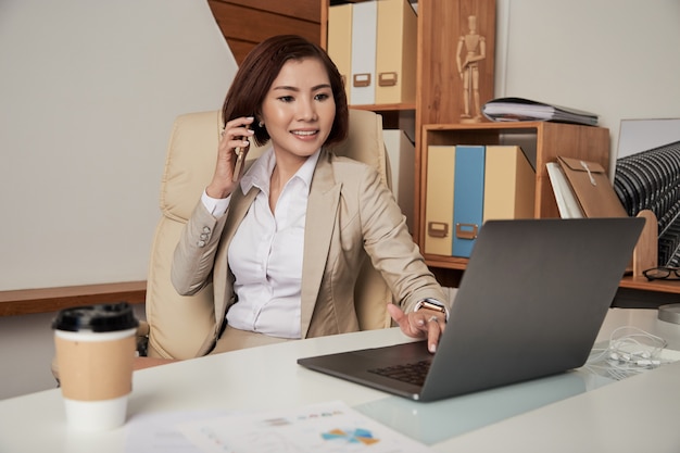 Zekere etnische onderneemster die op telefoon in bureau spreekt