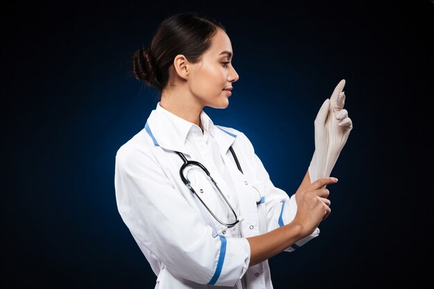 Zekere glimlachende arts die medische geïsoleerde handschoenen draagt