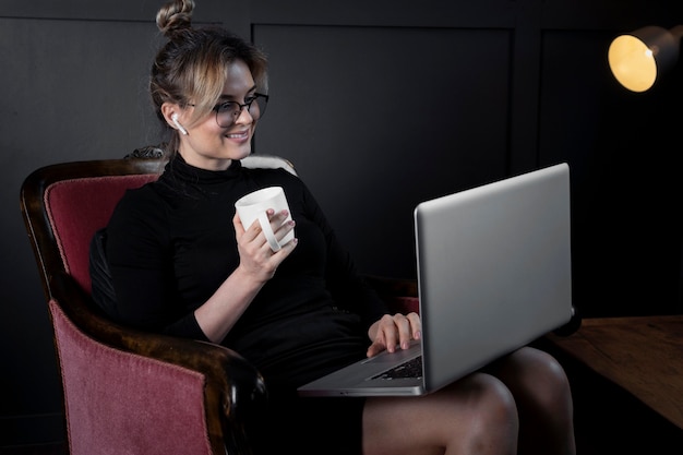 Zekere jonge vrouw die aan haar laptop op het kantoor werkt