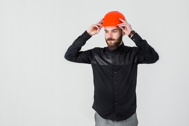 Zekere mannelijke architect die heldere oranje bouwvakker draagt