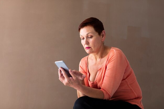 Zekere rijpe vrouw het doorbladeren telefoon