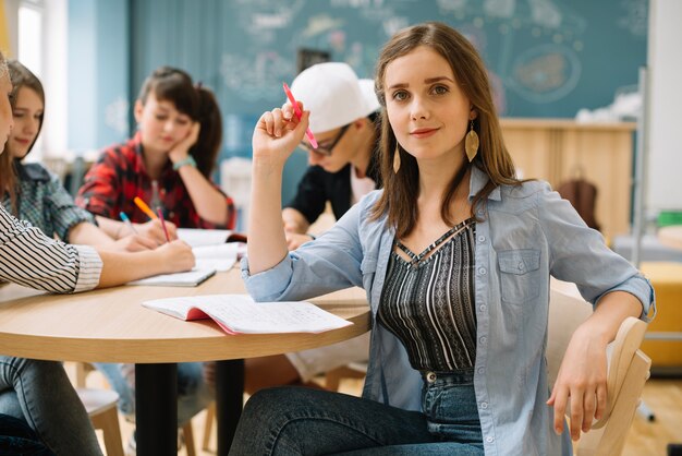 Zekere schoolmeisje aan tafel met klasgenoten