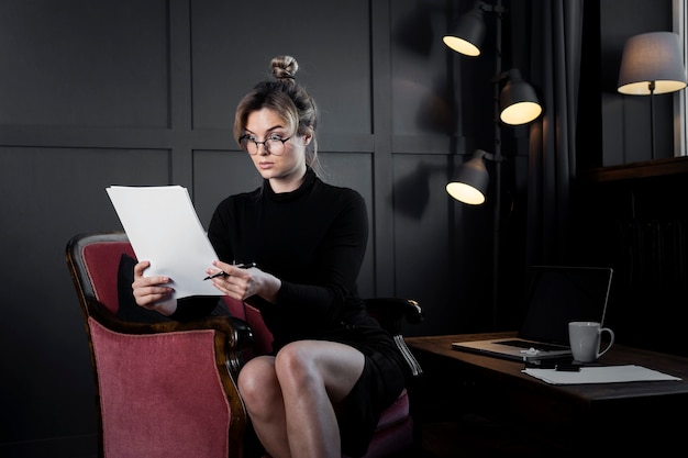 Zekere volwassen vrouw die sommige documenten controleert