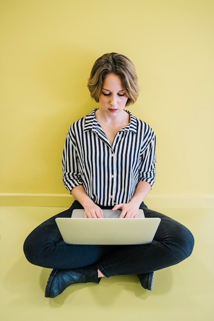 Zekere vrouwen doorbladerende laptop op geel