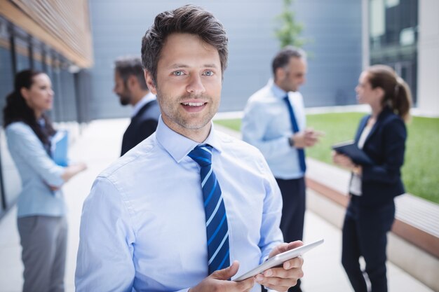 Zekere zakenman die digitale tablet buiten de bureaubouw houden