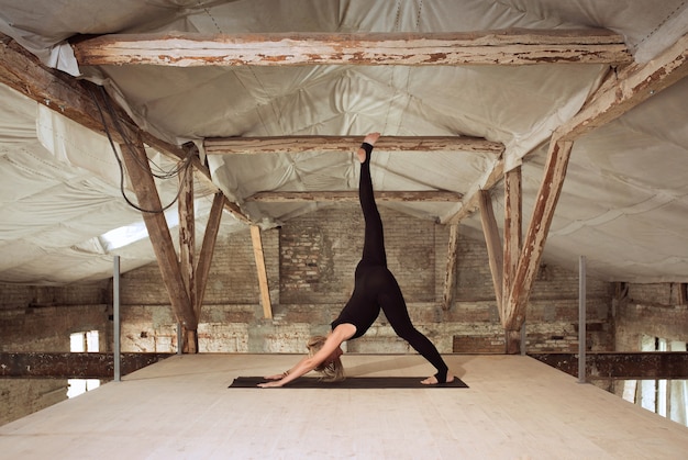 Zelfbouw. een jonge atletische vrouw oefent yoga op een verlaten bouwgebouw. geestelijke en lichamelijke gezondheid. concept van een gezonde levensstijl, sport, activiteit, gewichtsverlies, concentratie.