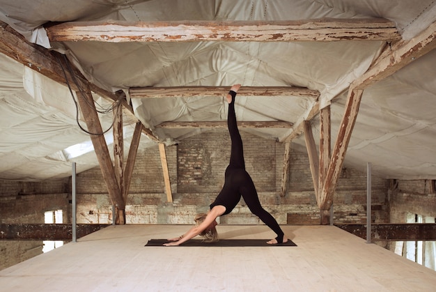 Zelfbouw. Een jonge atletische vrouw oefent yoga op een verlaten bouwgebouw. Geestelijke en lichamelijke gezondheid. Concept van een gezonde levensstijl, sport, activiteit, gewichtsverlies, concentratie.