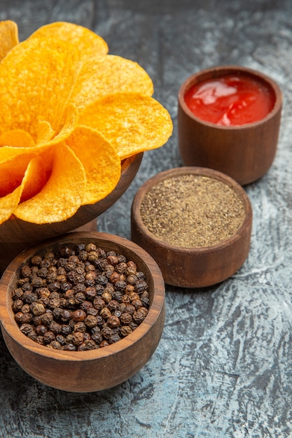 Zelfgemaakte aardappelchips versierd als bloemvormig en verschillende kruidenketchup op grijze tafel