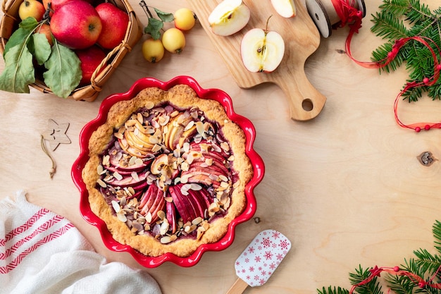 Gratis foto zelfgemaakte cake met cranberryjam en verse rode appels op een houten achtergrond appeltaart voor nieuwjaar en kerstmis