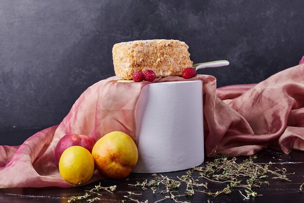 Zelfgemaakte cake op donkere achtergrond met bessen en pruimen en roze tafellaken.