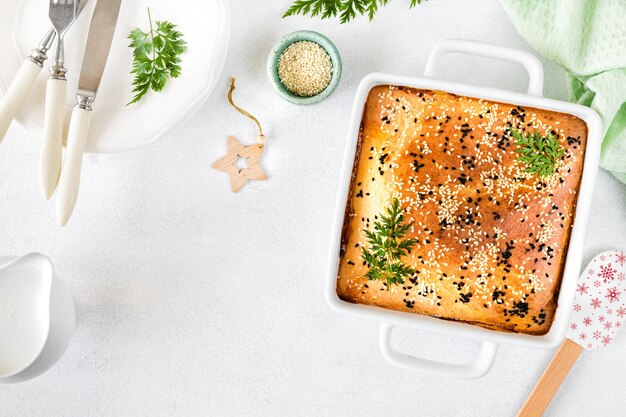 Zelfgemaakte gesloten taart met groenten op een witte betonnen ondergrond Ingrediënten voor een kool- en worteltaart op tafel