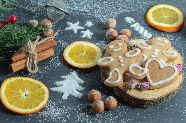 Zelfgemaakte koekjes op een houten bord met verschillende decoraties. Noten, sneeuw en sinaasappelschijfjes.