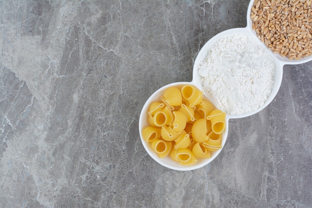 Zelfgemaakte pasta's met ingrediënten in witte ceramische kopjes