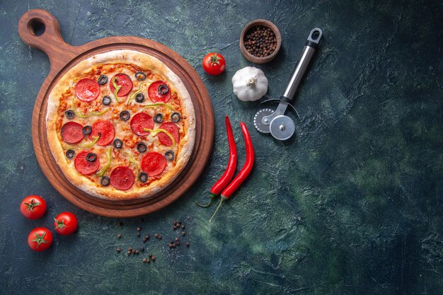 Zelfgemaakte pizza op houten snijplank en peper knoflook tomaten op geïsoleerde donkere ondergrond