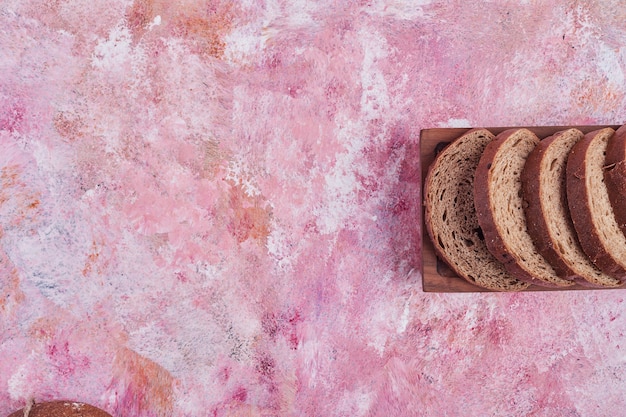 Zelfgemaakte sneetjes brood op een houten bord.