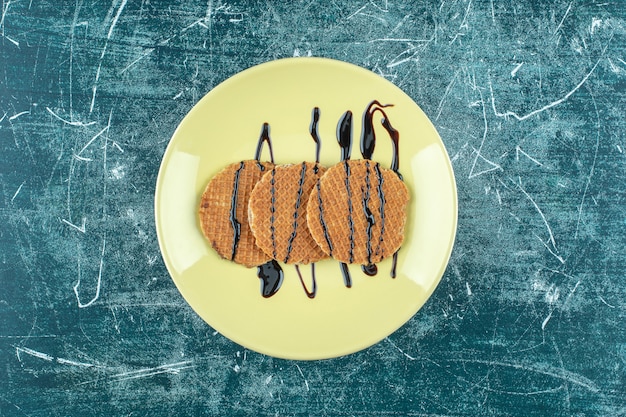 Zelfgemaakte wafel op een bord, op de blauwe tafel.