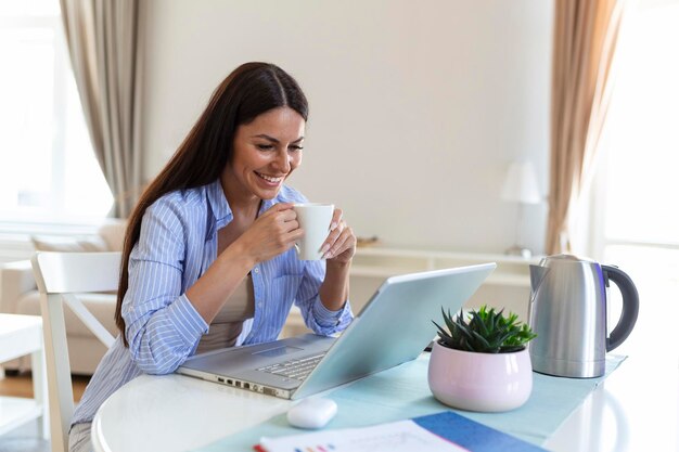 Zelfstandige vrouw aan het werk met haar laptop thuis met een kopje koffie