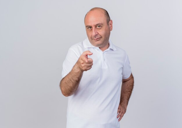 Zelfverzekerd casual volwassen zakenman hand zetten taille en wijzend op camera geïsoleerd op een witte achtergrond met kopie ruimte