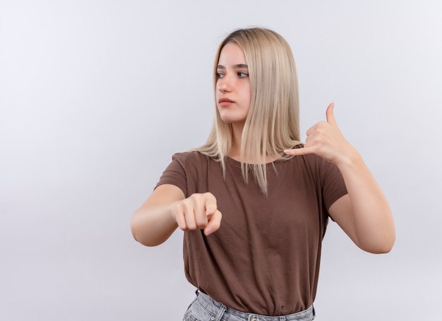 Gratis foto zelfverzekerd jong blond meisje doet roepnaam en wijst naar de linkerkant op geïsoleerde witte ruimte met kopie ruimte