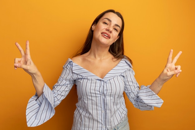 Zelfverzekerd vrij blanke vrouw gebaren overwinning handteken met twee handen op oranje